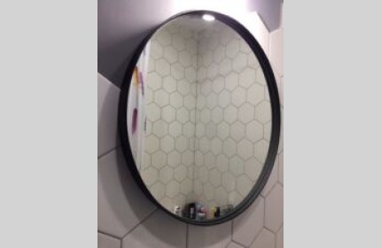 Кругле дзеркало в чорній рамі діаметром 60 см